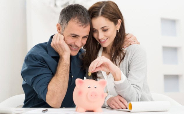 A couple putting money in a piggy bank