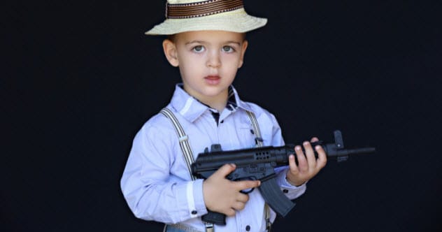 A toddler playing with a gun