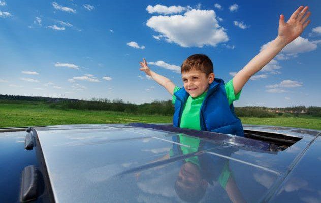 Boy looking out the sunroof of a car