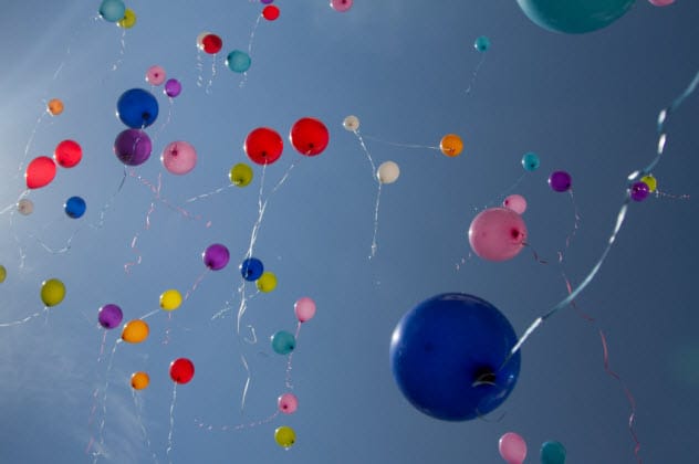 Colorful balloons floating into a blue sky, symbolizing a memorial during lockdown