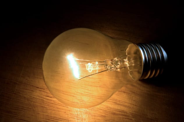 Glowing incandescent light bulb against a dark background