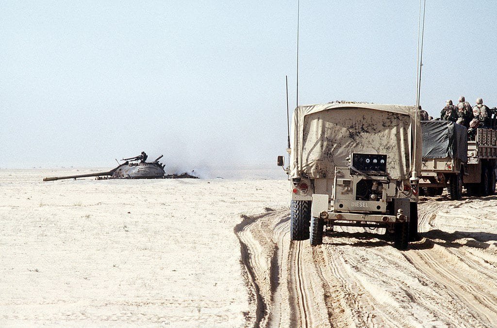 US convoy passes a destroyed Iraqi T-55 tank during the Gulf War