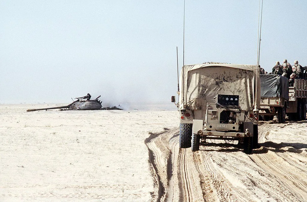 US convoy passes a destroyed Iraqi T-55 tank during the Gulf War