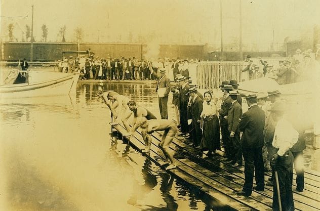Swimmers diving into a murky, man-made lake for a race at the 1904 St. Louis Olympics