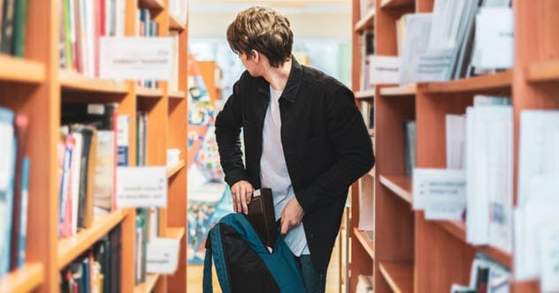 A person stealing a book from a library