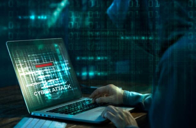 Hooded figure typing on a laptop, representing a movie hacker