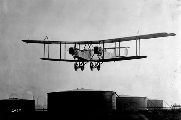 Early airplane in flight, a biplane over a landscape
