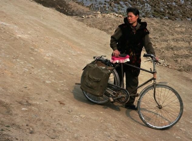 North Korean woman with a bicycle, highlighting gender inequality