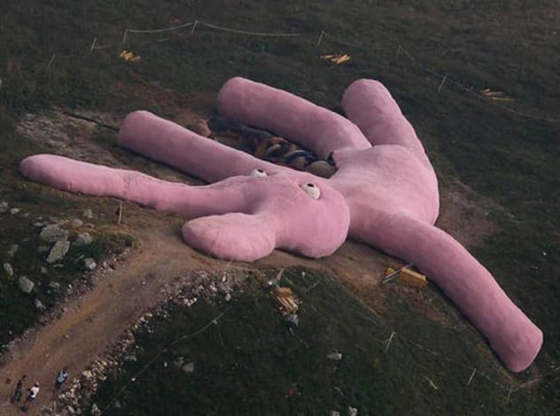A giant pink knitted rabbit lying on a hillside in the Italian Alps.