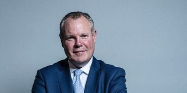 Conor Burns MP, a man in a suit, looking serious.