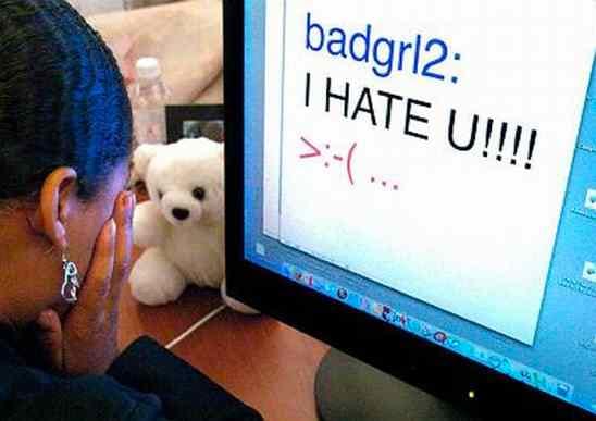 Silhouette of a person typing on a laptop with the words cyber bully