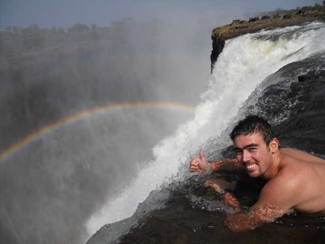 People swimming at the very edge of Victoria Falls in Devil's Pool.