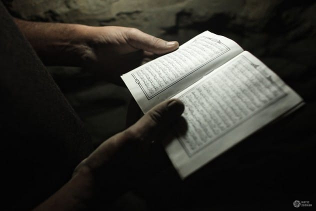 Person reverently holding a Quran, demonstrating proper handling