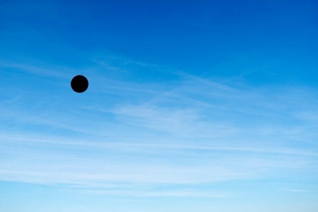 Dark sphere UFO emitting orange beams of light