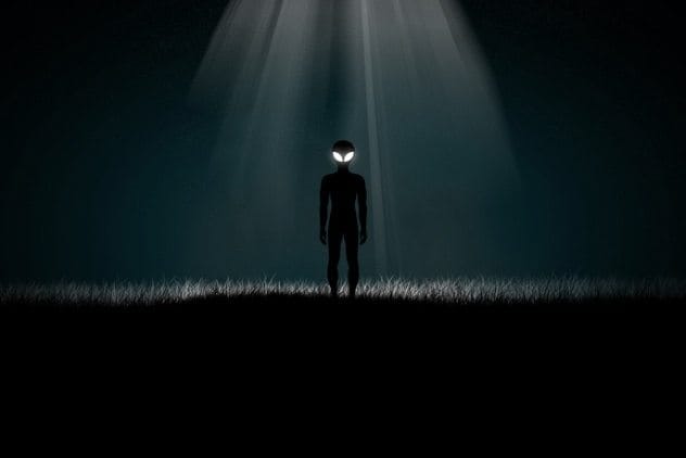 Car on a road with a UFO hovering nearby shining a light