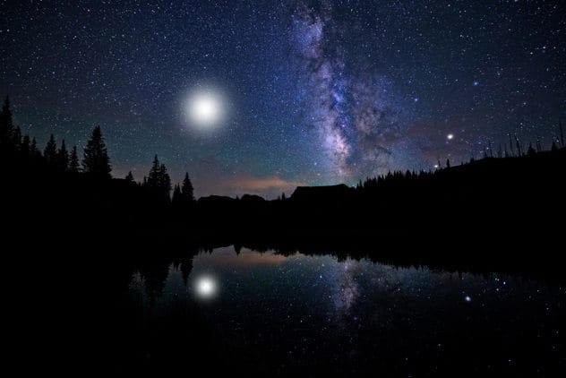 Luminous UFO rising from a lake with a figure inside