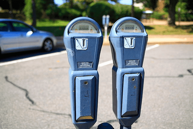 Two people dressed as fairies feeding a parking meter