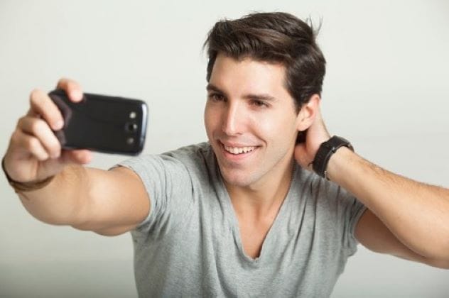 Man taking a selfie with a smartphone, looking pleased