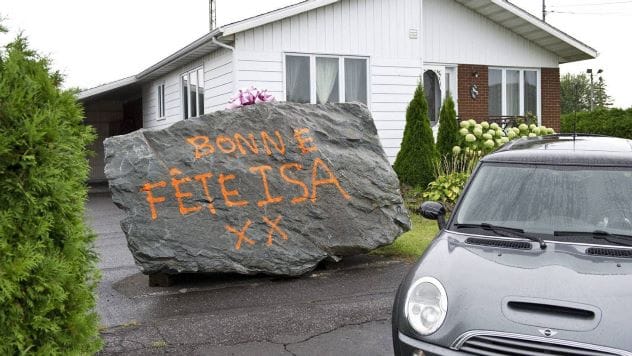 Large boulder spray-painted with 'Happy Birthday' on a lawn