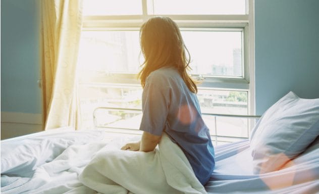 Woman in a hospital bed with family visiting