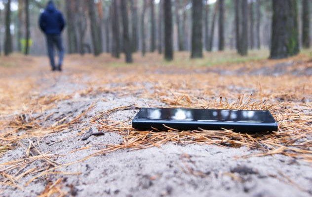 A wooden trail marker in a forest, indicating a hiking path in the mountains.