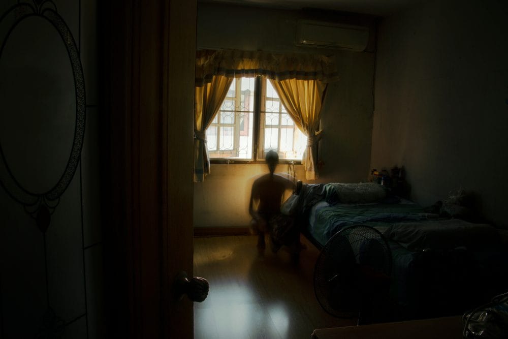 Sinister shadow of a person hiding under a bed