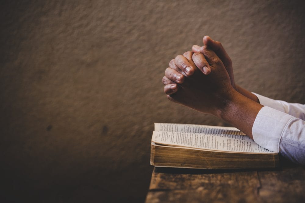 Hands in prayer, representing the unusual circumstances of a roommate's death.