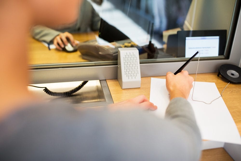 Person signing a document at a bank counter, illustrating a robber's bizarre negotiation