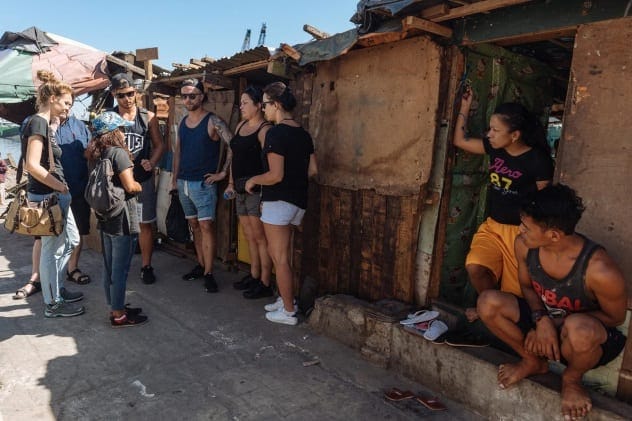 A group of tourists walking through a densely populated slum area