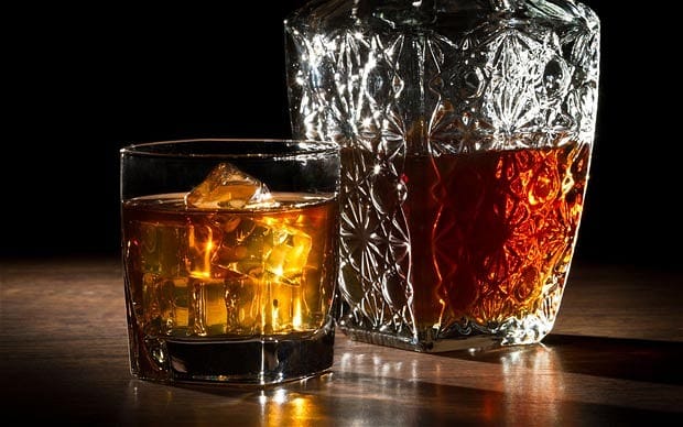 Glass of whiskey next to a bottle, highlighting the aging process